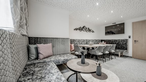 A modern dining room with a cozy seating area and elegant tables. The walls are decorated with stylish accents and a mountain graphic. - Appartementhaus Kathrin - Sölden