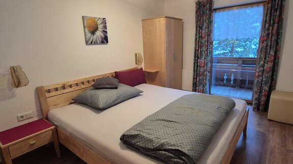 Ein gemütliches Schlafzimmer mit einem großen Bett und Holzmöbeln. Die Fenster bieten einen Blick auf einen Balkon mit natürlichem Licht. - Appt. Wildschütz - Sölden