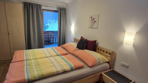 Ein gemütliches Schlafzimmer mit einem Doppelbett und bunten Bettwäsche. Das Zimmer hat Fenster mit Vorhängen und ist hell beleuchtet. - Appt. Wildschütz - Sölden