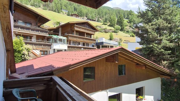 Eine gemütliche Balkonsicht auf traditionelle Holzhäuser und grüne Hügel. Der Himmel ist blau und die Umgebung ist sonnig. - Appt. Wildschütz - Sölden