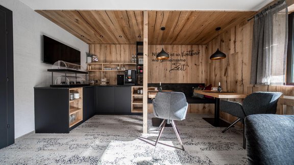 Ein modernes Wohnzimmer mit Holzwänden und einem offenen Küchenbereich. Es gibt einen Esstisch, Stühle und gemütliche Sitze. - Bianca`s BB - Sölden
