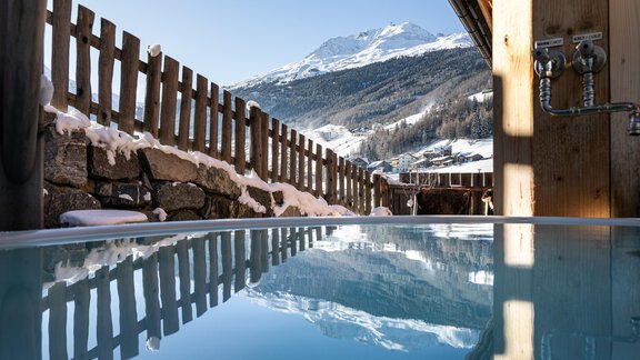 Ein entspannender Außenwhirlpool mit Blick auf schneebedeckte Berge. Die klare Wasseroberfläche spiegelt die schöne Landschaft wider. - Chalet Resort Sölden - Sölden
