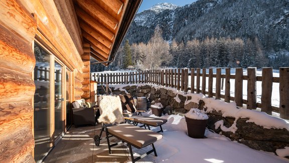 Eine gemütliche Terrasse mit Liegen und einem Blick auf verschneite Berge. Die Holzstruktur und der umzäunte Bereich verleihen eine alpine Atmosphäre. - Chalet Resort Sölden - Sölden