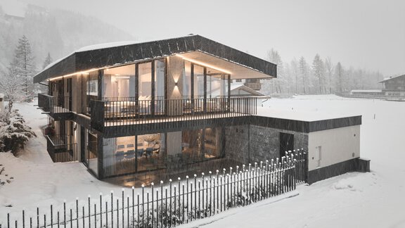 Ein modernes Haus im Schnee mit großen Fenstern und einem Balkon. Die winterliche Landschaft ist mit frischem Schnee bedeckt. - Chalet White Pearl by MYALPS - Sölden