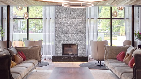 Ein stilvoll eingerichteter Raum mit bequemen Sofas und einem modernen Kamin. Große Fenster lassen viel Licht herein und schaffen eine einladende Atmosphäre. - Chalet White Pearl by MYALPS - Sölden