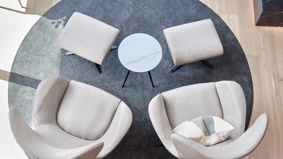 Ein eleganter Sitzbereich mit zwei bequemen Sesseln und einem kleinen Tisch in der Mitte. Der Boden ist hell und modern gestaltet. - Chalet White Pearl by MYALPS - Sölden