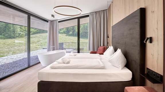 Ein modernes Schlafzimmer mit einem großen Fenster und Blick auf die Natur. Das Zimmer ist stilvoll eingerichtet mit einem Doppelbett und gemütlichen Möbeln. - Chalet White Pearl by MYALPS - Sölden
