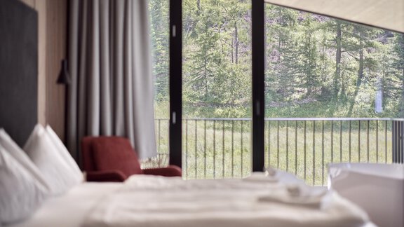 Ein modernes Hotelzimmer mit Blick auf die grünen Bäume draußen. Das Zimmer ist hell und freundlich eingerichtet. - Chalet White Pearl by MYALPS - Sölden