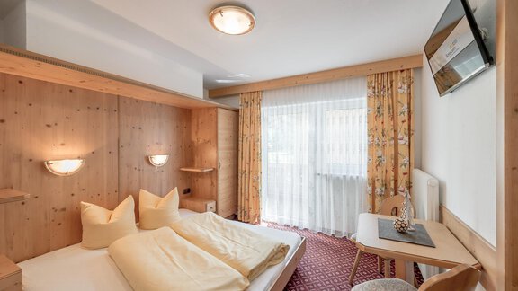 Ein gemütliches Hotelzimmer mit Holzverkleidung und zwei Betten. Der Raum hat ein Fenster mit Vorhängen und einen kleinen Schreibtisch. - Ferienhaus Apart Sonnzeit - Sölden