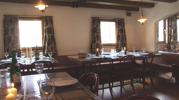 A cozy dining room with wooden ceilings and large windows. Tables are lovingly set with glasses and dishes for a festive atmosphere. - Ferienhaus Innerwald - Sölden