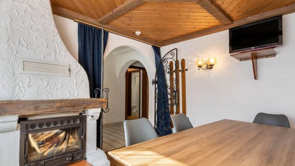 Ein gemütlicher Raum mit einem Holztisch, Stühlen und einem Kamin. Die Wände sind hell und die Decke ist mit Holz verkleidet. - Garni Nadine - Sölden