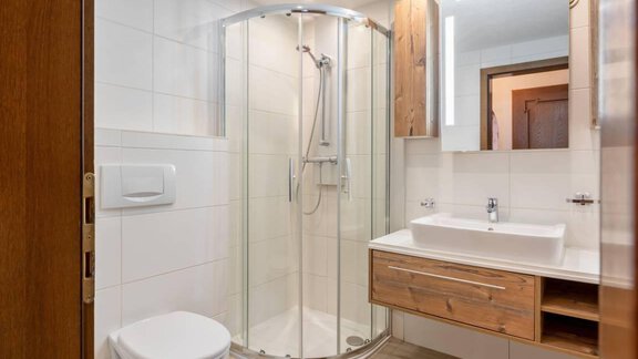 Ein modernes Badezimmer mit Dusche und Holzdetails. Das Waschbecken ist elegant und der Raum wirkt hell und freundlich. - Garni Nadine - Sölden