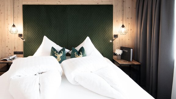 A modern bedroom with a comfortable bed and elegant wooden design. The pillows are tastefully decorated, and the surroundings exude coziness. - Garni Rustica - Sölden