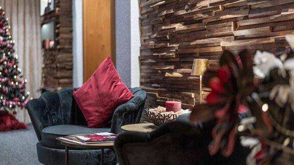 Ein stilvoller Wohnraum mit einer gemütlichen Couch und einem runden Tisch. Im Hintergrund steht ein geschmückter Weihnachtsbaum. - Gästehaus Maier - Sölden