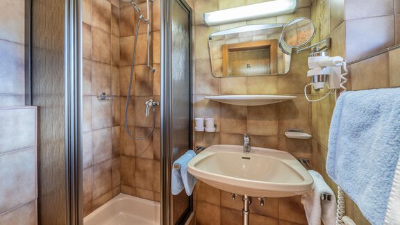 Ein kleines Badezimmer mit einer Dusche und einem Waschbecken. Die Wände sind in warmen Brauntönen gehalten. - Gästehaus Maier - Sölden