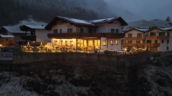 Eine charmante Berghütte mit warmem Licht und festlicher Beleuchtung. Der schneebedeckte Hintergrund vermittelt eine gemütliche Winteratmosphäre. - Gasthof Granstein - Sölden