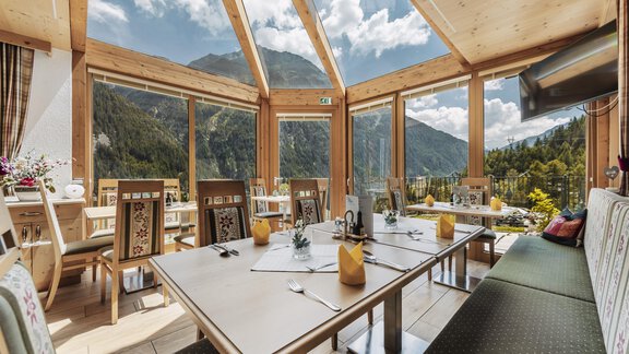 Ein helles Restaurant mit großen Fenstern und Blick auf die Berge. Tische sind für Gäste vorbereitet und eine gemütliche Atmosphäre ist spürbar. - Gasthof Granstein - Sölden