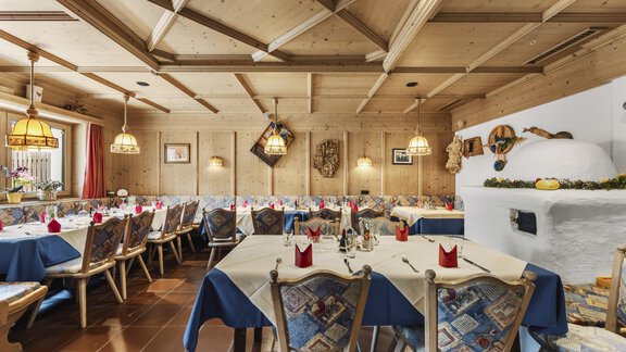 Ein gemütliches Restaurant mit Holzdecken und stilvollen Lampen. Die Tische sind mit blauen Tischtüchern und roten Servietten gedeckt. - Gasthof Granstein - Sölden