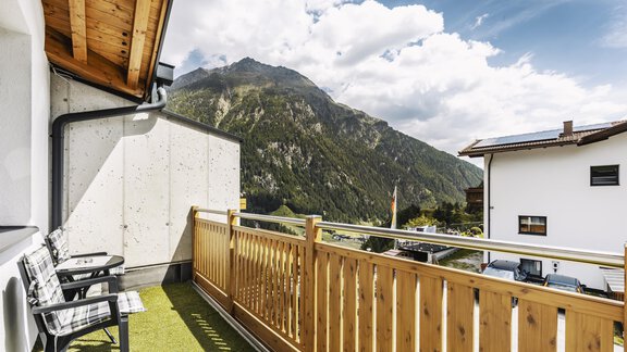 Ein Balkon mit Holzgeländer und Stühlen. Im Hintergrund sind majestätische Berge und ein klarer Himmel zu sehen. - Gasthof Granstein - Sölden