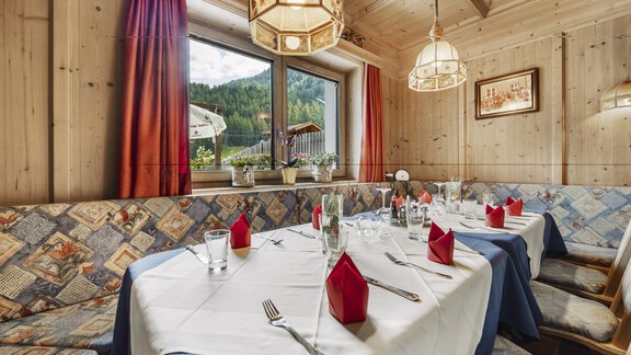 Ein schön gedeckter Tisch in einem gemütlichen Restaurant mit Holzverkleidung. Rote Servietten und Gläser ergänzen die einladende Atmosphäre. - Gasthof Granstein - Sölden