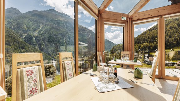 Eine helle und gemütliche Restaurantumgebung mit großen Fenstern und Blick auf die Berge. Der Tisch ist für Gäste gedeckt, umgeben von einer einladenden Atmosphäre. - Gasthof Granstein - Sölden