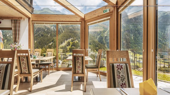 Ein lichtdurchflutetes Restaurant mit großen Fenstern und Blick auf die Berge. Die Tische sind gemütlich eingerichtet und laden zum Verweilen ein. - Gasthof Granstein - Sölden