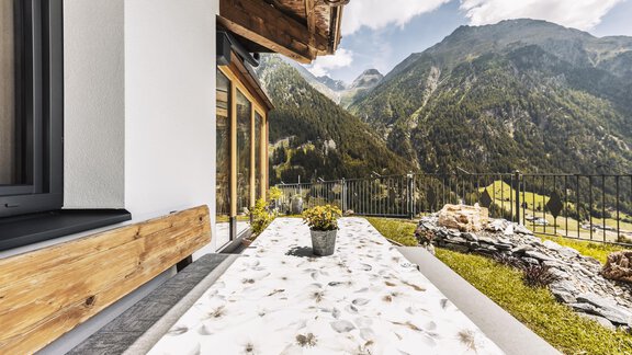 Eine moderne Terrasse mit Blick auf die Berge. Der Boden ist mit einem dekorativen Muster versehen und es steht ein Topf mit Pflanzen auf dem Tisch. - Gasthof Granstein - Sölden
