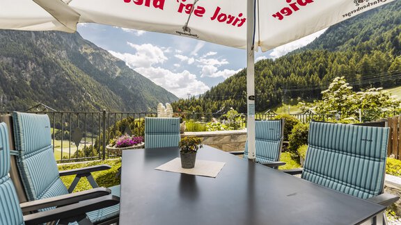 Ein schöner Außenbereich mit Blick auf die Berge. Der Tisch ist ordentlich gedeckt und von Stühlen umgeben. - Gasthof Granstein - Sölden