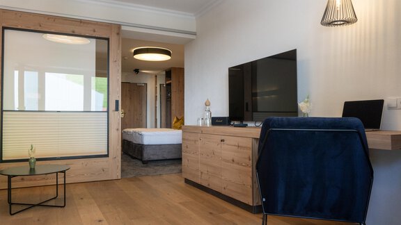 A modern room with wood veneer and a large television. The decor is simple and cozy, ideal for relaxation. - Glanz & Glory Hotel - Sölden