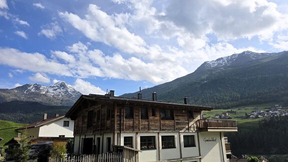 Ein charmantes Holzhaus liegt in der Alpenlandschaft. Im Hintergrund sind majestätische Berge und ein klarer Himmel zu sehen. - Granbichlhof - Sölden
