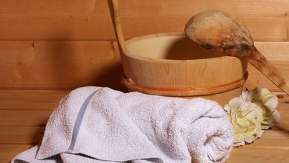 A cozy set with a wooden container, a wooden spoon, and a folded towel. Next to the towel lies a flower that creates a relaxing atmosphere. - Haus am Wildbach - Sölden