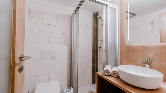 Ein modernes Badezimmer mit Dusche und Waschbecken. Es gibt handtücher auf einem Holzregal und helle, neutrale Farben. - Haus Crystal - Sölden