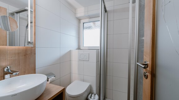 Ein modernes Badezimmer mit einer Dusche, einem Waschbecken und einer Toilette. Die Wände sind gefliest und das Licht ist hell. - Haus Crystal - Sölden