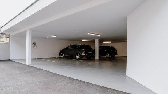 Eine moderne Tiefgarage mit hellen Wänden und zwei parkenden Autos. Die Beleuchtung sorgt für eine freundliche Atmosphäre. - Haus Crystal - Sölden