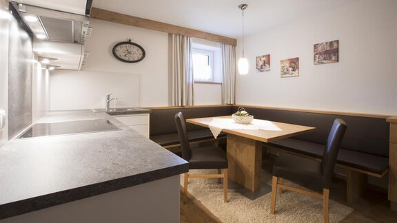 Eine moderne Küche mit einem gemütlichen Essbereich. Der Tisch ist mit einer kleinen Dekoration gedeckt und es hängen Bilder an der Wand. - Haus Madeleine - Sölden