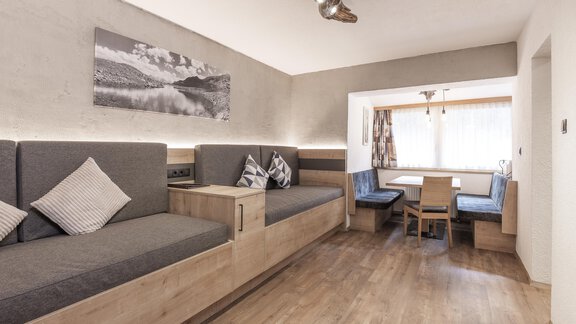 Ein modernes Wohnzimmer mit gemütlichen Sitzgelegenheiten und einem Essbereich. Die Wände sind hell und es gibt große Fenster, die viel Licht hereinlassen. - Haus Manfred - Sölden