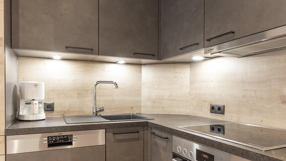 Eine moderne Küche mit grauen Schränken und Edelstahlgeräten. Das Licht schafft eine gemütliche Atmosphäre. - Haus Manfred - Sölden