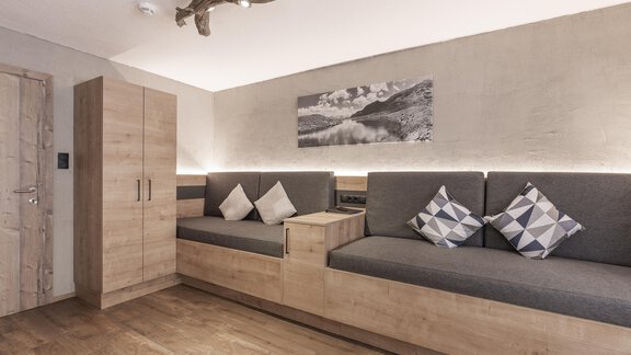 Ein modernes Wohnzimmer mit einem gemütlichen Sitzbereich und Kissen. Die Wände sind in neutralen Farben gehalten und es gibt einen schönen Holzfußboden. - Haus Manfred - Sölden