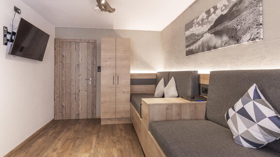 Ein modernes Zimmer mit Holzdekor und gemütlichen Sitzecken. An der Wand hängt ein Fernseher und ein Bild einer Landschaft. - Haus Manfred - Sölden