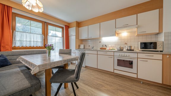A modern kitchen with a dining area and plenty of natural light. The kitchen is fully equipped and feels very cozy. - Haus Nicola - Sölden