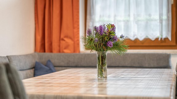 A cozy dining area. The room has orange curtains and a bright, inviting atmosphere. - Haus Nicola - Sölden