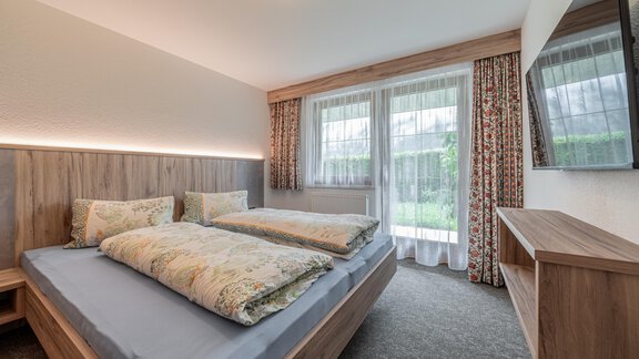 A modern bedroom with a double bed and large windows. - Haus Nicola - Sölden