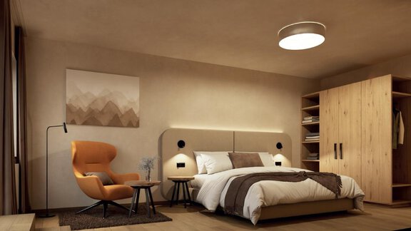 Ein modernes Schlafzimmer mit einem großen Bett, einem gemütlichen Sessel und einem Kleiderschrank. Die Wände sind in neutralen Farben gehalten und ein Kunstwerk ziert die Wand. - Hotel Garni Hainbacherhof - Sölden
