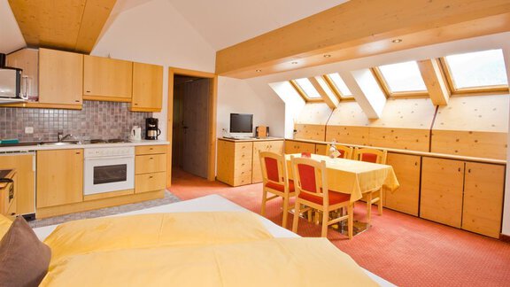 Ein gemütliches Zimmer mit einem Doppelbett, einer Küchenzeile und einem Esstisch. Große Fenster sorgen für viel Tageslicht und eine angenehme Atmosphäre. - Hotel Garni Hainbacherhof - Sölden