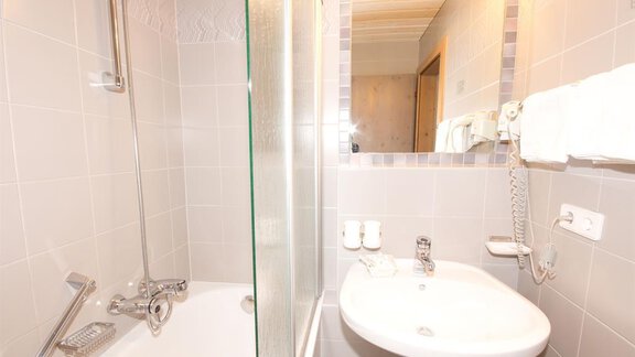 Ein modernes Badezimmer mit Dusche und Badewanne. Es sind Handtücher und grundlegende Sanitäranlagen vorhanden. - Hotel Garni Hainbacherhof - Sölden