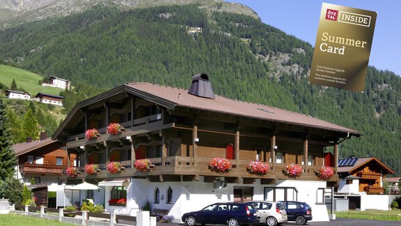 Ein charmantes Gebäude in den Alpen mit blühenden Blumen auf dem Balkon. Im Hintergrund sind grüne Berge und ein blauer Himmel sichtbar. - Hotel Garni Maria Theresia - Sölden