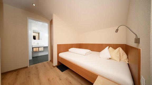 Ein einfaches Schlafzimmer mit einem Einzelbett und einem großen Fenster. Der Raum hat helle Wände und einen minimalistischen Stil. - Hotel Garni Maria Theresia - Sölden