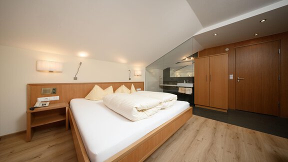 Ein modernes Schlafzimmer mit einem großen Doppelbett und Holzvertäfelungen. Die Wände sind hell und der Raum wirkt gemütlich und einladend. - Hotel Garni Maria Theresia - Sölden