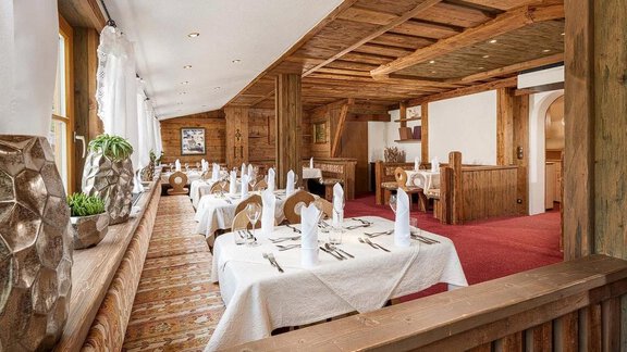 An elegant restaurant with wooden interior and nicely set tables. Large windows provide plenty of daylight and an inviting atmosphere. - Hotel Sunny Sölden - Sölden