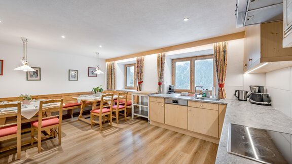 Eine moderne Küche mit einem großen Essbereich. Helle Farben und viel Tageslicht sorgen für eine einladende Atmosphäre. - Lyns Home - Sölden